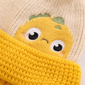 Detailed macro view of beige and yellow knit hat with cute dinosaur embroidery texture