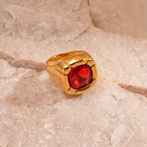 Close-up of a vintage gold ring with a square red zircon set on a textured stone