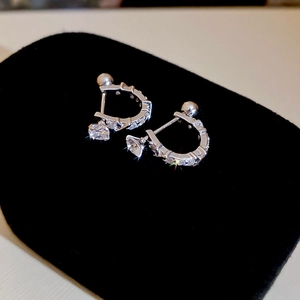 Macro shot of silver U-shaped earrings with sparkling cubic zirconia on black velvet