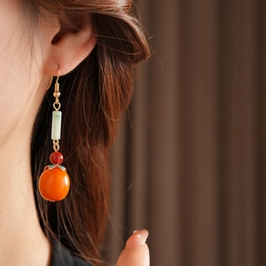 Close-up of a Persimmon drop earring with red and orange beads on a model