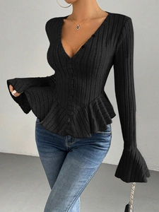 Detail of V-neck button closure on black ribbed knit top with elegant ruffled hem