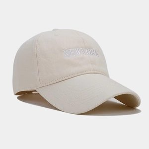 Close-up of white NEW YORK embroidery on a cream cotton twill baseball cap