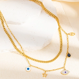 Détail d'un collier multicouche en acier doré avec pendentifs œil et étoile