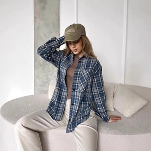 Gros plan sur une chemise à carreaux bleu et gris avec top marron et casquette verte
