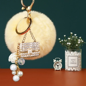 Detailed view of yellow faux fur pompom keychain with rhinestone bag and pearl charms