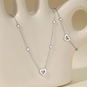 Elegant stainless steel heart necklace set for women on beige ceramic hand display