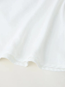 Gros plan d'une robe longue sans manches blanche montrant la texture du tissu et l'ourlet