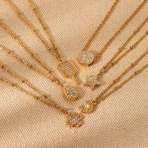 Close-up of 18K gold-plated necklaces with clover, star, and moon crystal charms