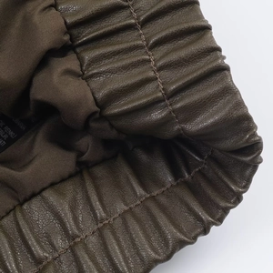 Detail einer dunkelbraunen Bomberjacke aus Kunstleder mit elastischem Bund und feiner Textur