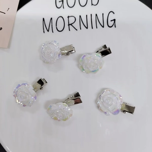 Detail view of five iridescent white camellia hair clips on a decorative white ceramic plate