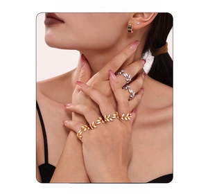 Detailed close-up of gold and silver leaf rings with white enamel and zircon accents