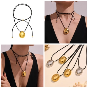Detailed view of polished oval metal pendant on black cord in gold and silver finishes
