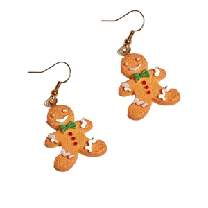 Festive gingerbread man earrings with green bowties and golden hooks on white background