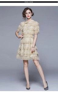 Close-up of the delicate floral lace texture and ruffled layers on the beige dress