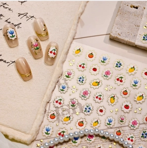 Detail of 3D embossed fruit nail art stickers with cherry and tulip patterns and gold trim