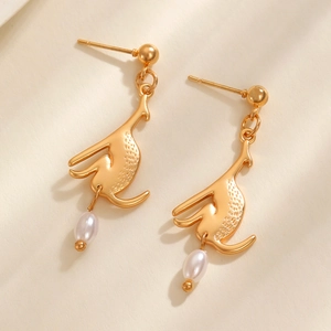 Boucles d'oreilles chat dorées créatives avec perles sur fond texturé beige doux