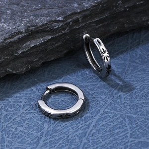 Macro shot of silver stainless steel hoop earrings with black floral star engravings