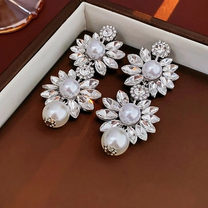 Detailed macro of flower earrings with crystals and large teardrop pearl pendants