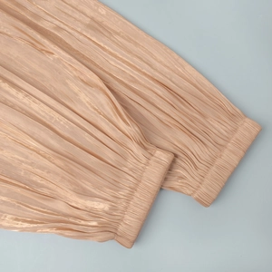 Detailed macro view of pleated champagne satin fabric with vertical plissé texture