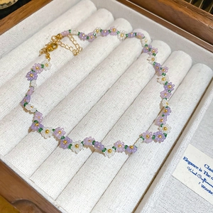 Detail of handmade purple and white beaded flower bracelet in a wooden jewelry box