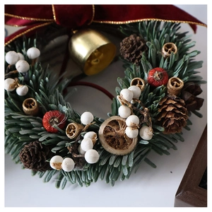 Close-up of Christmas wreath with pine needles, red berries, cones, and a golden bell