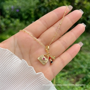 Dettaglio del ciondolo placcato oro 18K con borsa shopping, rossetto e charm di lusso