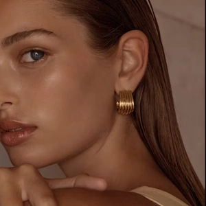 Close-up of model wearing gold layered stripe earrings with a polished metallic finish