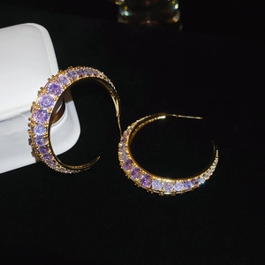 Macro shot of gold-plated hoop earrings featuring sparkling purple zircon stones