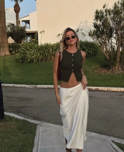 Détails du gilet en maille vert foncé à boutons et de la jupe midi en satin crème