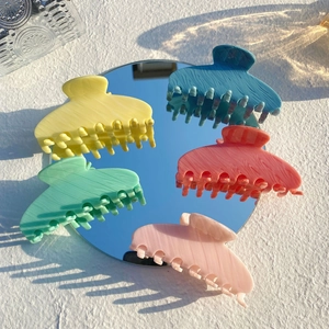 Grandes pinces à cheveux Y2K en acétate en cinq couleurs disposées autour d'un miroir