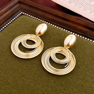 Macro shot of gold spiral hoop earrings resting on an elegant dark vintage jewelry tray