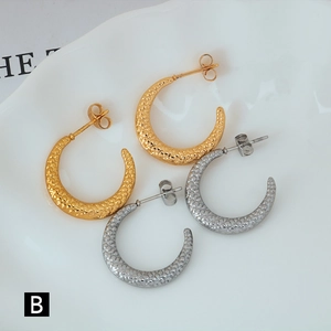 Detail view of gold and silver C-shaped hoop earrings with embossed scale texture
