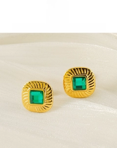 Detail shot of vintage square emerald zircon earrings on soft white silk fabric background