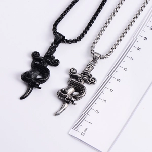 Detailed comparison of black and silver snake sword pendants with ruler measurement
