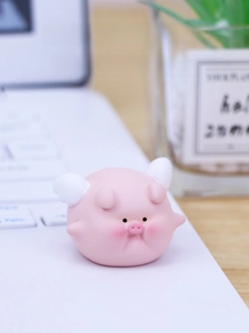 Close-up of cute pink flying pig resin figurine with small wings on a desktop laptop