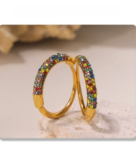 Detail of PVD gold plated hoop earrings with multicolored zircon crystals on stone