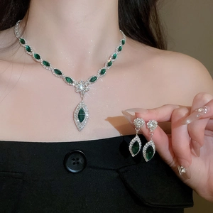 Close-up of luxury water drop jewelry set with green gemstones and diamonds worn by a model