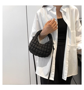 Detail of black quilted puffer bag in lightweight nylon shown on a model for scale