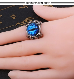 Detail of a punk dragon claw ring featuring a deep blue evil eye gemstone on a finger