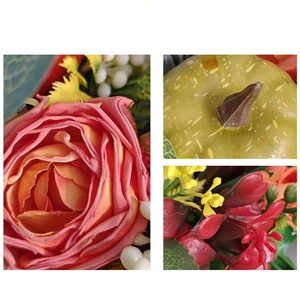 Close-up of artificial fall wreath with pink silk roses, mini pumpkins and berries