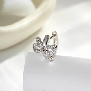 Elegant silver bow huggie hoop earrings with sparkling cubic zirconia on white background