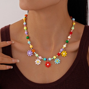 Close-up of a colorful floral beaded necklace featuring vibrant acrylic daisy charms on model
