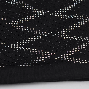 Macro shot of wave-patterned rhinestones on black knitted fabric with iridescent crystals