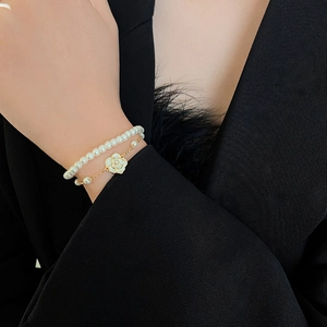 Detail of camellia pearl double-layer bracelet featuring white flowers and gold-plated alloy