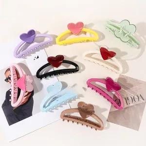 Flat lay of nine colorful heart-shaped hair claw clips on a stylish fashion magazine