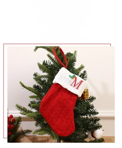 Detail of red knit Christmas stocking with embroidered letter M and holly on white cuff
