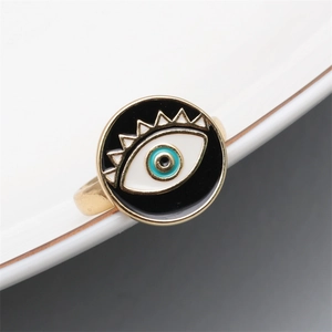 Detailed close-up of golden evil eye ring with blue enamel inlay on ceramic edge