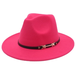 Détail d'un chapeau fedora rose rouge avec bande décorative noire et boucle dorée