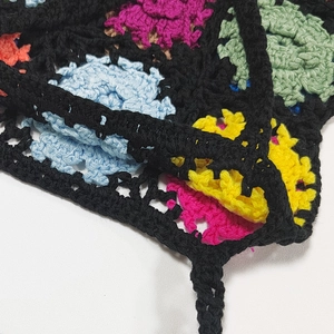 Close-up of handmade crochet granny square bag showing dense colorful stitching texture
