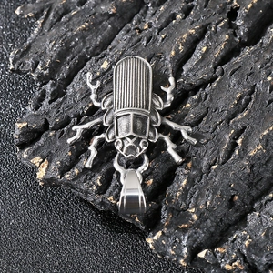 Macro shot of silver beetle pendant showing vintage textures and polished steel details